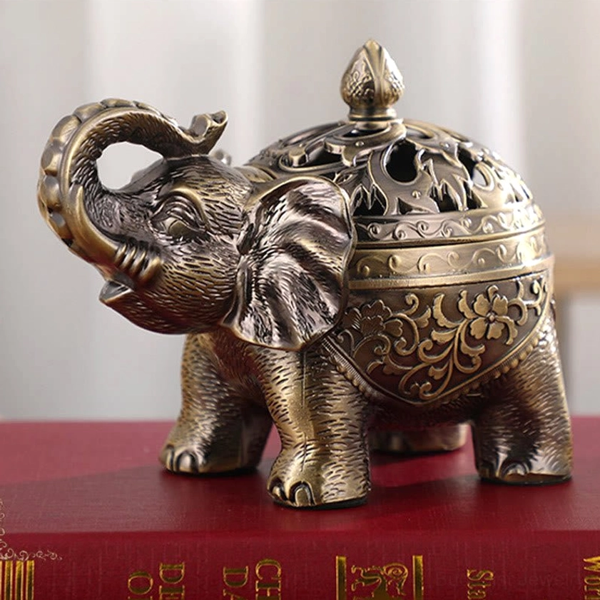 Front-facing view of brass-bronze elephant incense burner on red book base with detailed embossed floral patterns