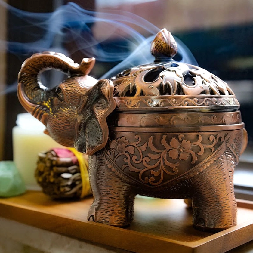 Elephant incense burner in use on home tabletop with fragrant smoke rising from dome lid, demonstrating meditation altar setup