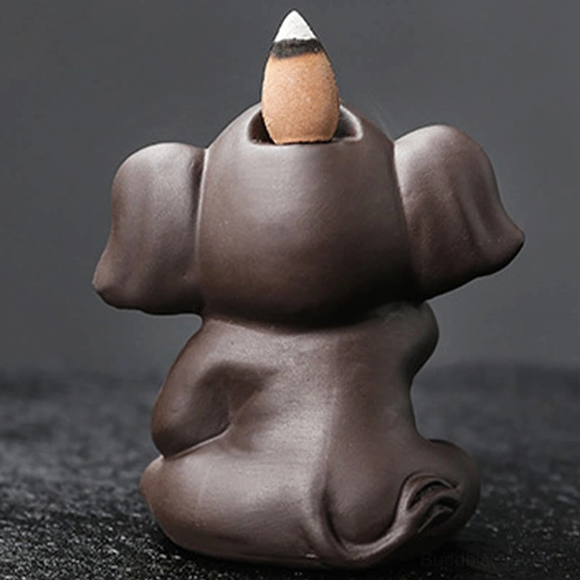 Rear view of handcrafted elephant incense burner showing incense cone slot on head top dark studio background detail shot