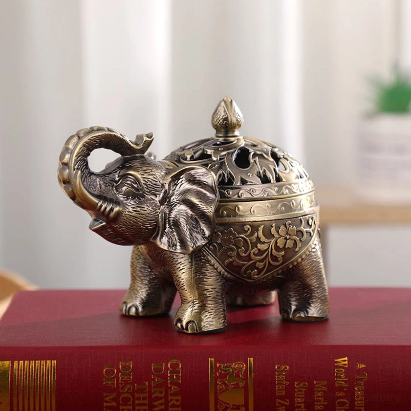Antique gold-bronze elephant incense holder displayed on red book desk showing artisanal floral metal carving and home décor appeal