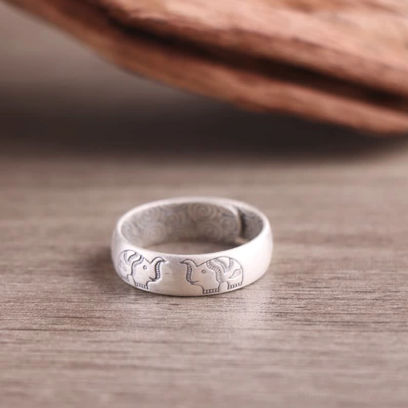 Elephant symbol sterling silver blessing ring with hand-engraved details and matte finish on wooden surface