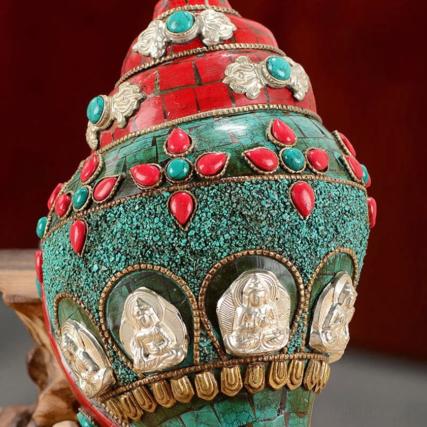 Ornate Buddhist conch shell with multiple embossed silver Buddha plaques, gemstone inlays, and green textured finish