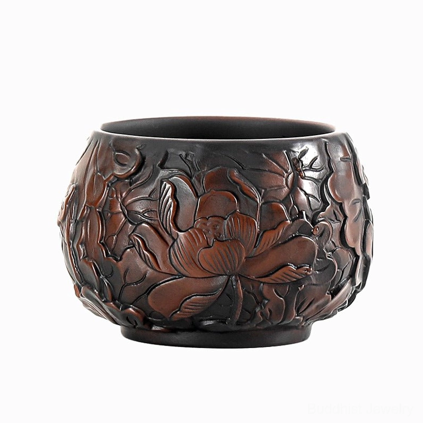 Side close-up of handcrafted ceramic cup with single embossed lotus flower motif and matte dark ceramic finish