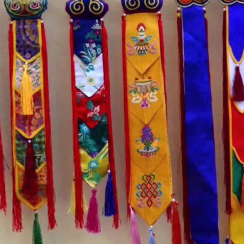 Close-up detail of embroidered Buddhist sacred symbols and multi-color silk tassels on fabric