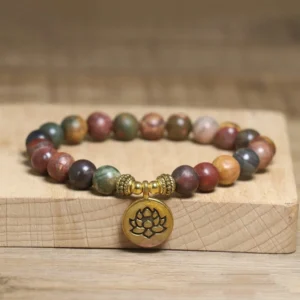 Emperor Stone lotus bracelet with gold metal lotus charm, natural variegated earthy stone beads on elastic band, displayed on wooden block