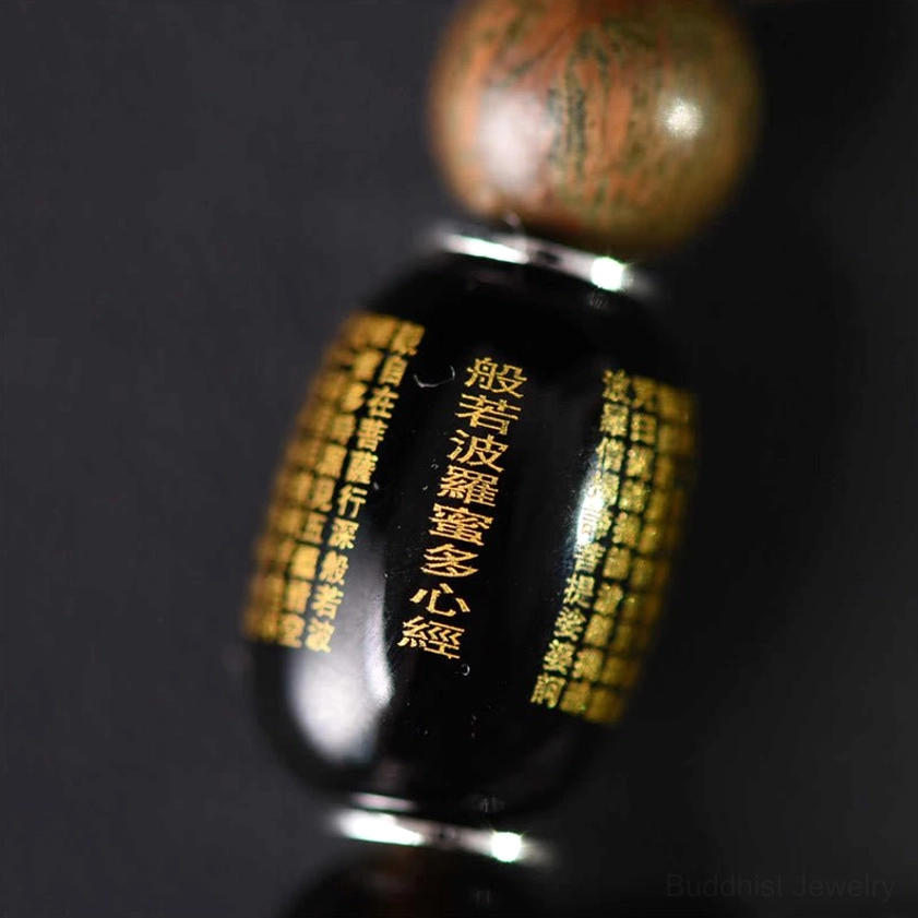 Engraved prayer bead with golden Buddhist scripture and metal trim showing craftsmanship detail