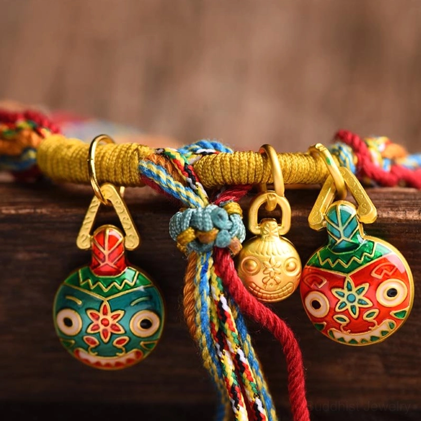 Buddhist family fortune bracelet charm set with enamel folk-style pendants, metal buckles and braided multicolor rope on wood table