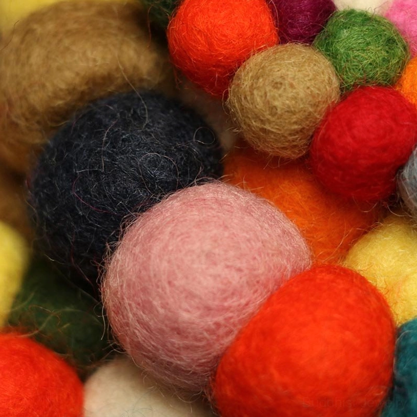 Extreme close-up macro shot of various solid-color fuzzy felted wool balls and fibers