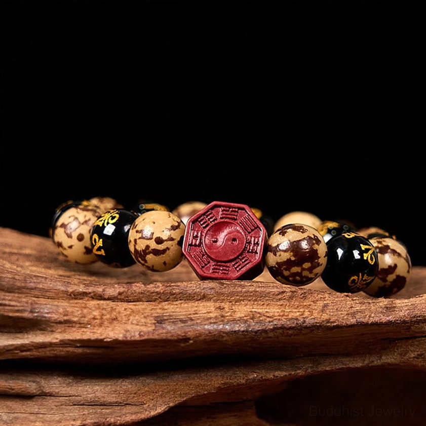 Feng Shui prayer bracelet with red cinnabar center charm and tri-color Bodhi seed beads on natural wood display
