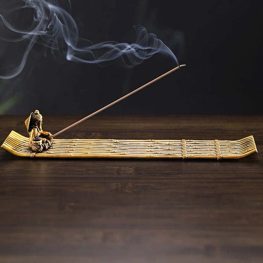 Three-quarter perspective of smoking fisherman incense burner on wooden surface with small fisherman figurine and woven bamboo base