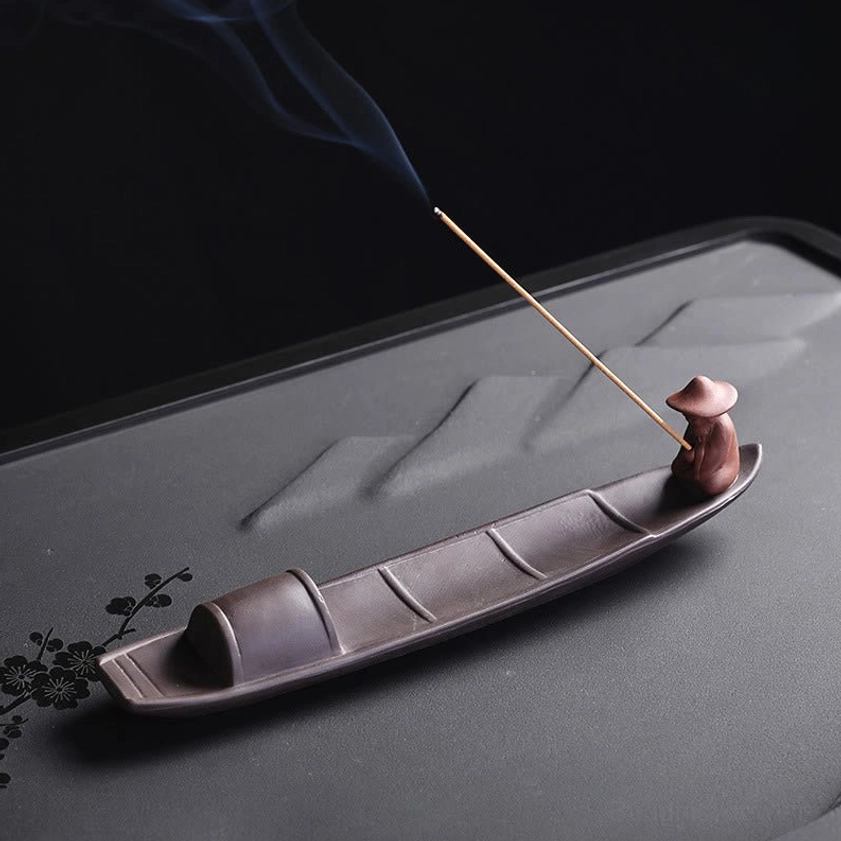 Buddhist incense holder with artisan fisher figurine wearing traditional straw hat, left side view showing authentic boat structure and incense smoke