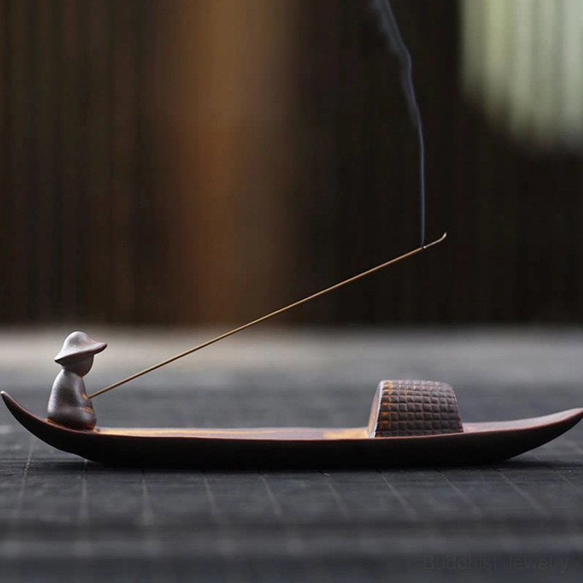 Handcrafted ceramic fisherman boat incense burner with woven cabin detail on wooden table, smoking incense stick