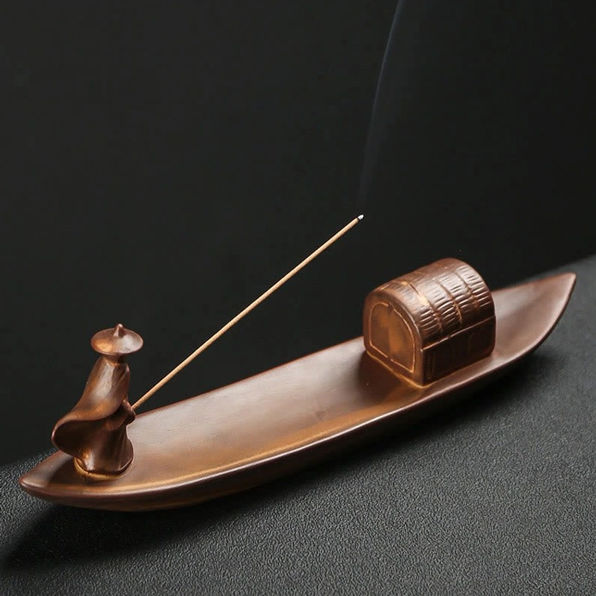 Fisherman boat ceramic incense burner emitting fragrant smoke, right angle view, matte vintage brown