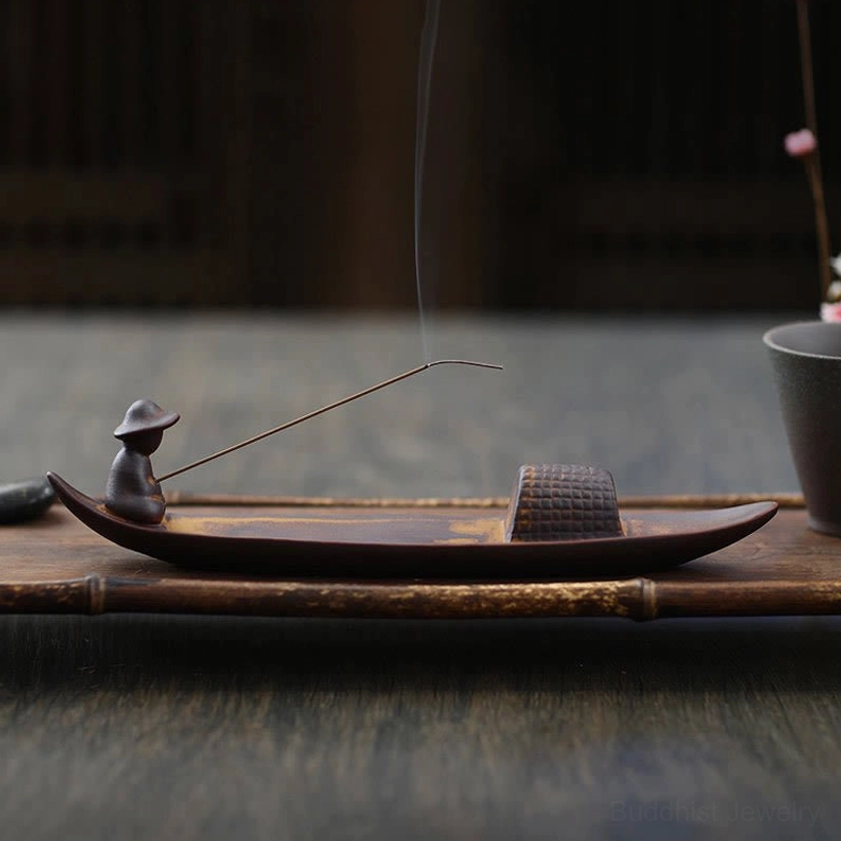 Handmade ceramic incense burner styled on bamboo tray with decorative potted plant on dark wood table