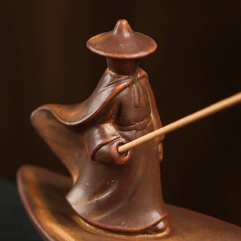 Close-up detail of handcrafted fisherman figurine wearing bamboo hat and flowing robe, ceramic artistry