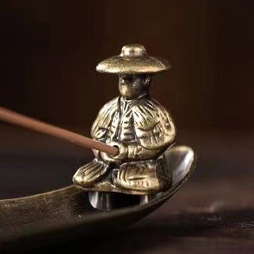 Close-up detail of traditional fisherman figurine on bronze incense holder holding an incense stick