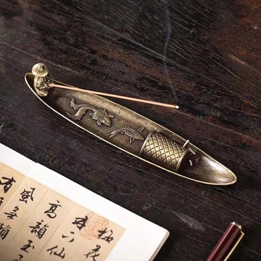 Side angle view of fishing boat incense burner with smoking stick on traditional study table, antique bronze finish