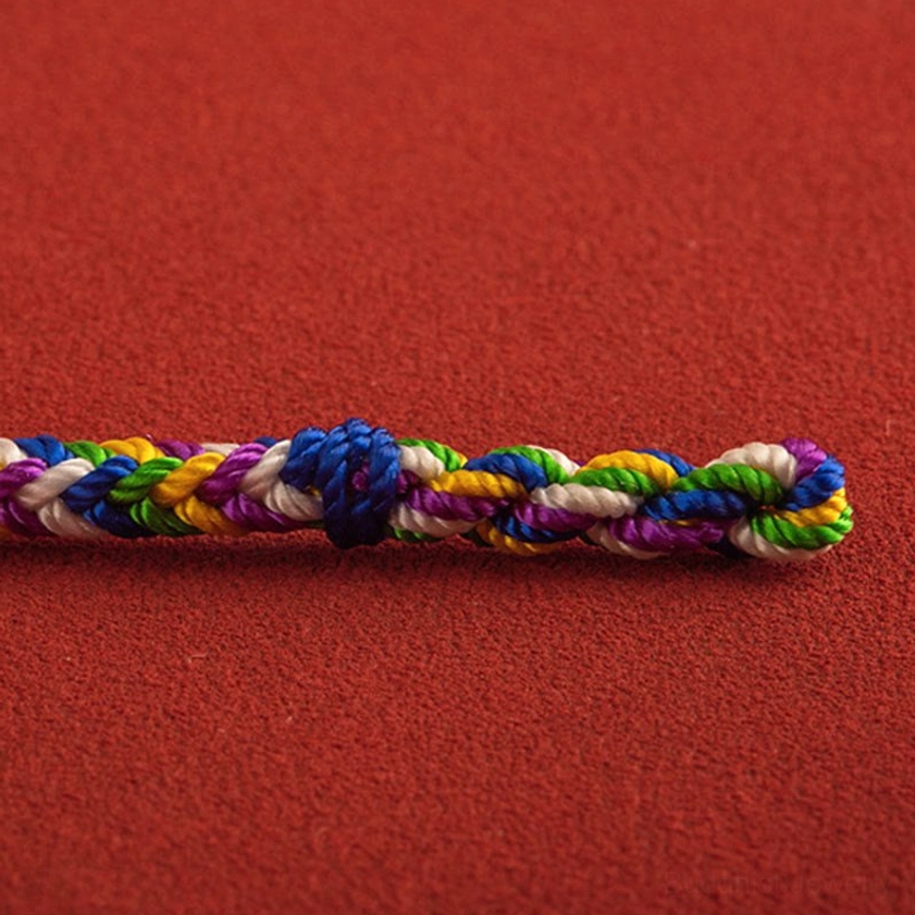 Multicolor woven bracelet segment showing five-thread braided pattern with central dark blue knot on red background