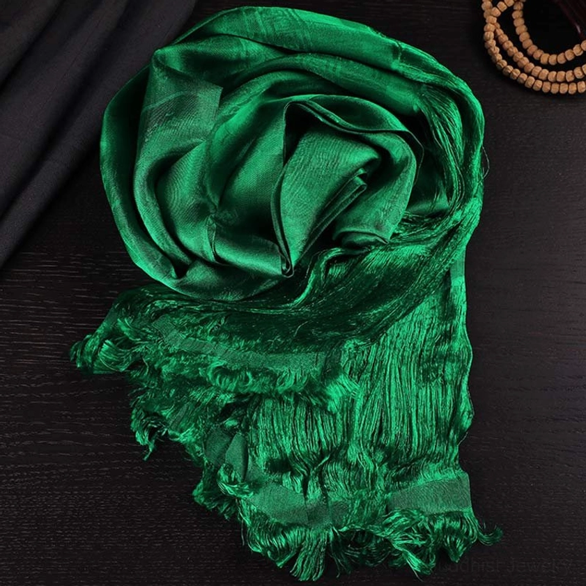 Deep green five-color Buddhist blessing khata scarf with jacquard weave and frayed tassels, displayed on dark wooden surface with meditation prayer beads