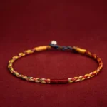 Handmade five-color Buddhist string bracelet with braided red thread and metal clasp, top-down flat lay view