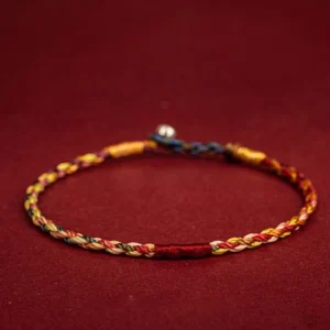 Handmade five-color Buddhist string bracelet with braided red thread and metal clasp, top-down flat lay view
