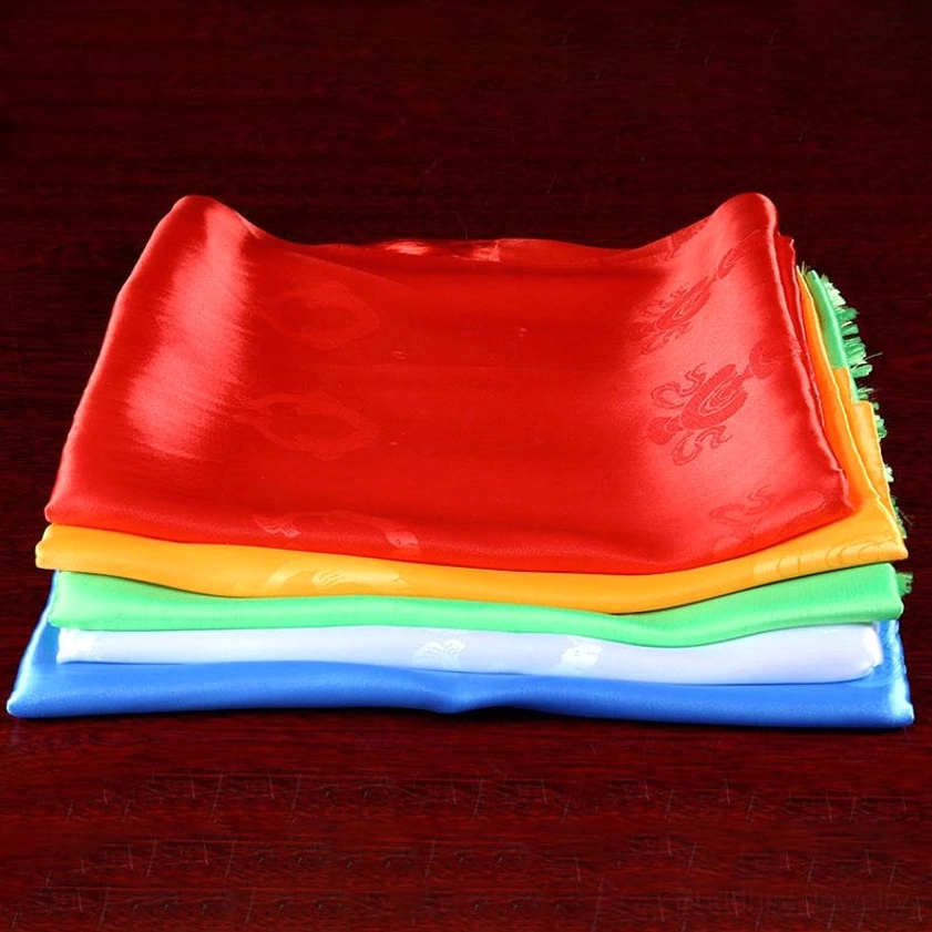 Neatly stacked five-color khata set overhead view on dark wooden table showing layered arrangement and embossed blessing patterns