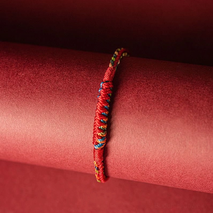 Red and multi-color braided Buddhist protection cord bracelet, side profile showing twisted weave pattern
