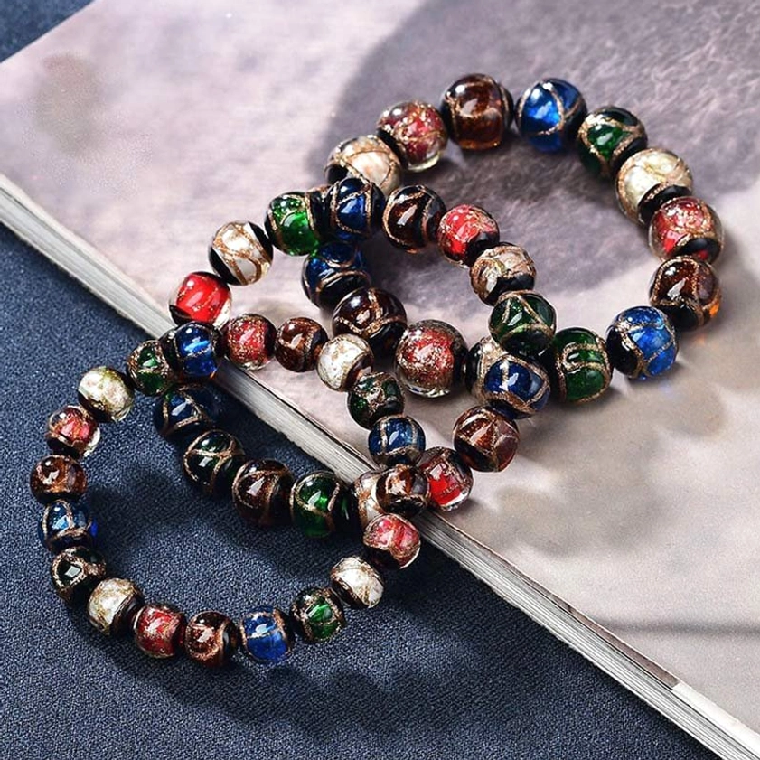 Two matching colorful liuli glass Buddhist bracelets with gold-trimmed beads in flat lay arrangement