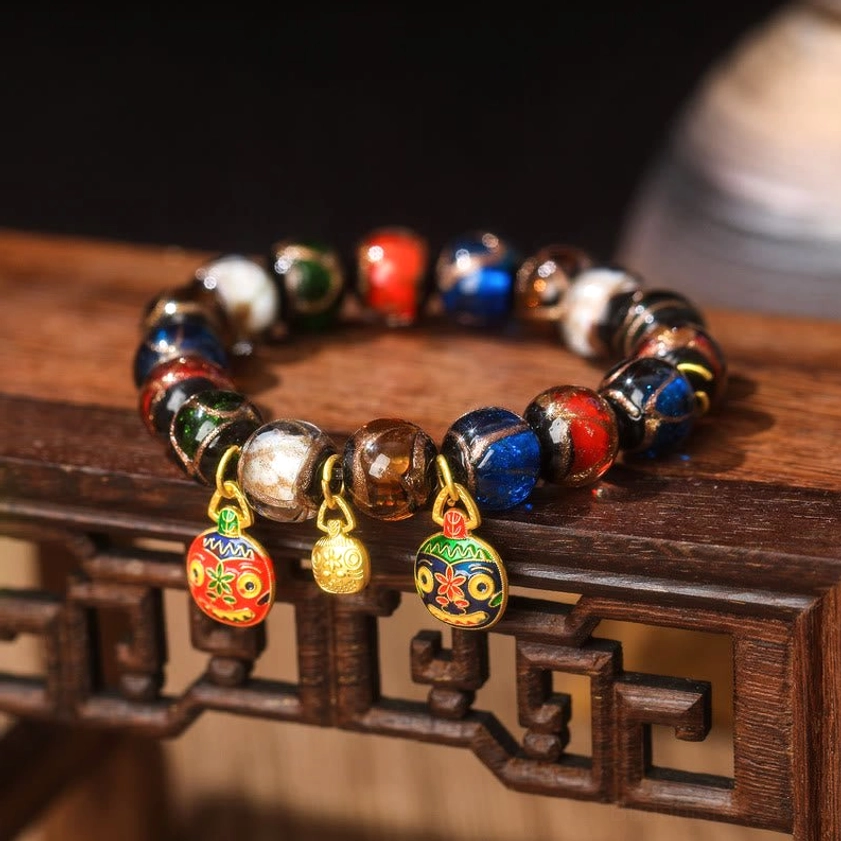 Five Elements Buddhist Liuli glass bead bracelet with red and green patterned enamel charms and gold bell – spiritual balance design