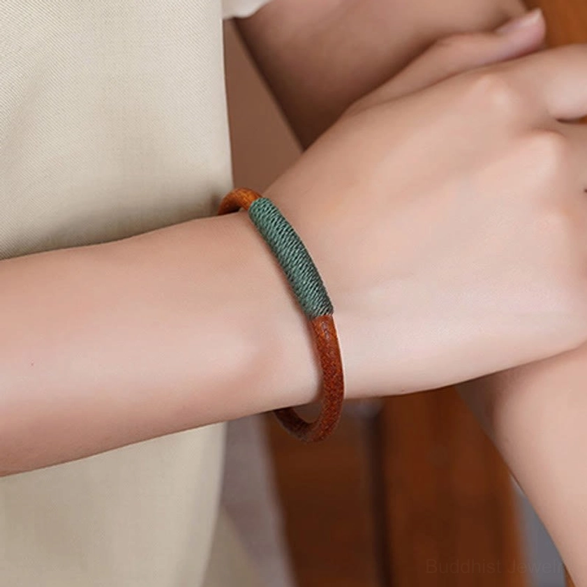 Five elements leather bracelet front view worn on wrist showing brown leather and woven accent in daily wear
