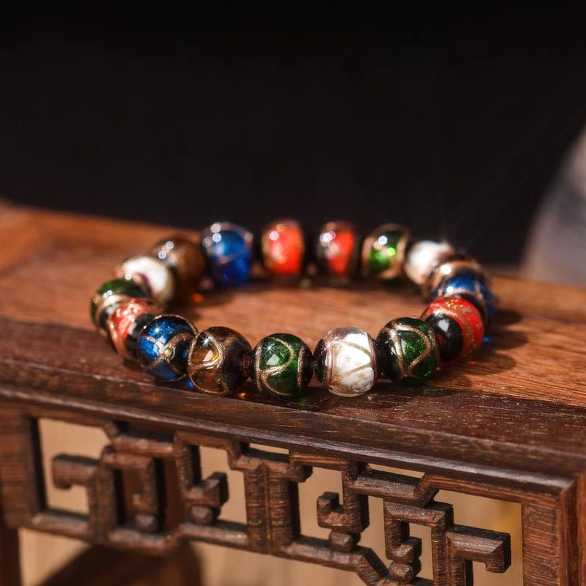 Single strand Five Elements Liuli glass bead bracelet without charms – close-up on wooden table showing smooth glazed beads