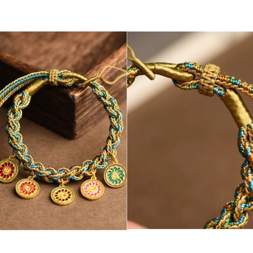 Five Gods of Wealth Buddhist bracelet overhead flat lay displaying five enamel gold pendants and traditional braided knot fastener on wooden desk