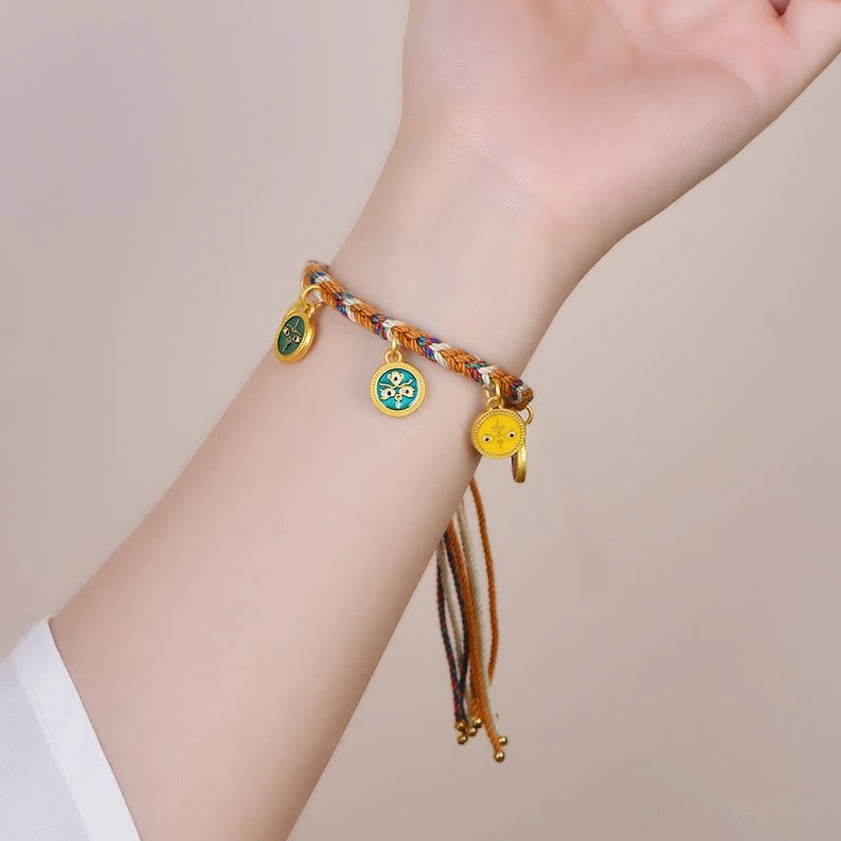 Buddhist prosperity bracelet being worn on human wrist showing comfortable fit of five enamel charms hanging from multicolor braided string with long tassels