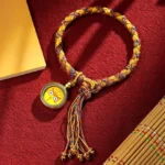 Five Gods of Wealth braided rope bracelet with yellow charm, gold-mixed braid and tassel details, handmade Buddhist prosperity bracelet