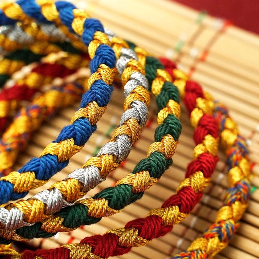 Coiled handmade Buddhist prosperity bracelets showing thick twisted rope construction and multiple color combinations for Five Gods of Wealth charm