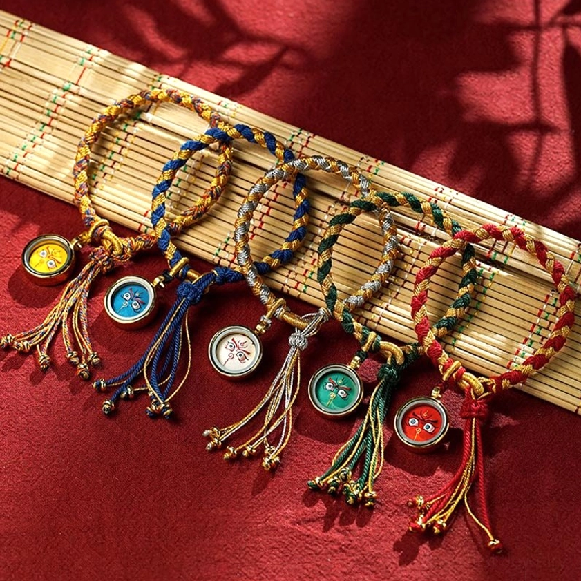 Multiple color variations of Buddhist Five Gods of Wealth braided bracelets displayed together, showing different colored round pendants and adjustable rope designs