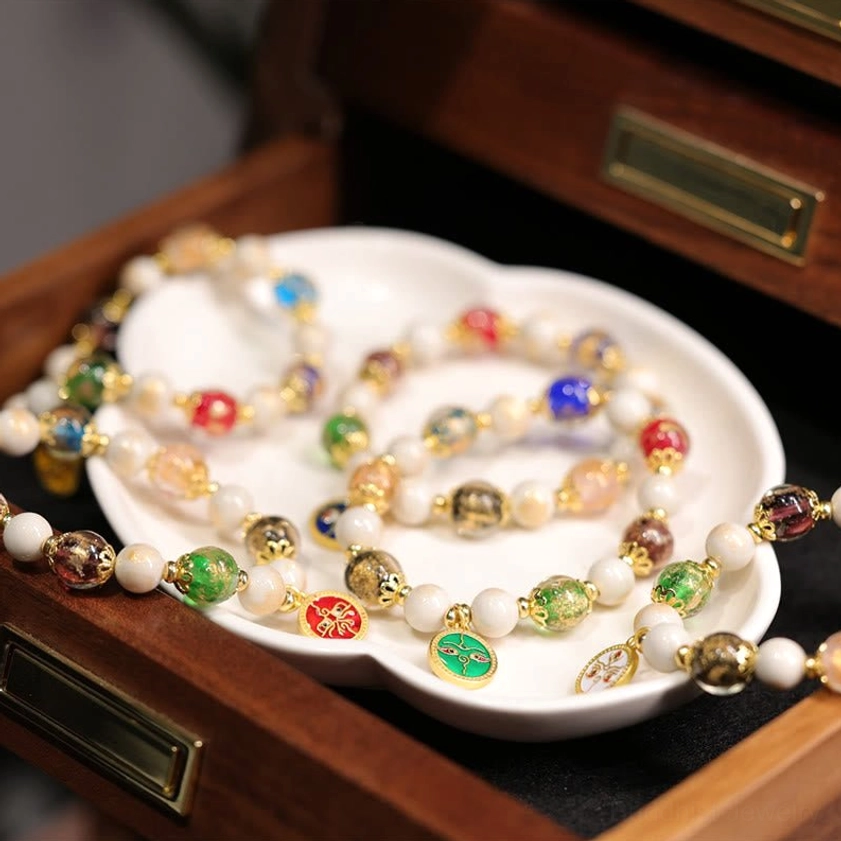 Multiple Five Gods of Wealth Buddhist bracelets with colorful enamel pendants and glass beads in wooden drawer storage