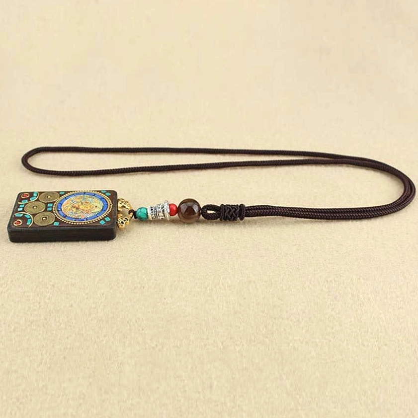 Five Gods of Wealth Thangka ebony pendant necklace side flat view, displaying carved deity artwork with decorative beads and braided cord