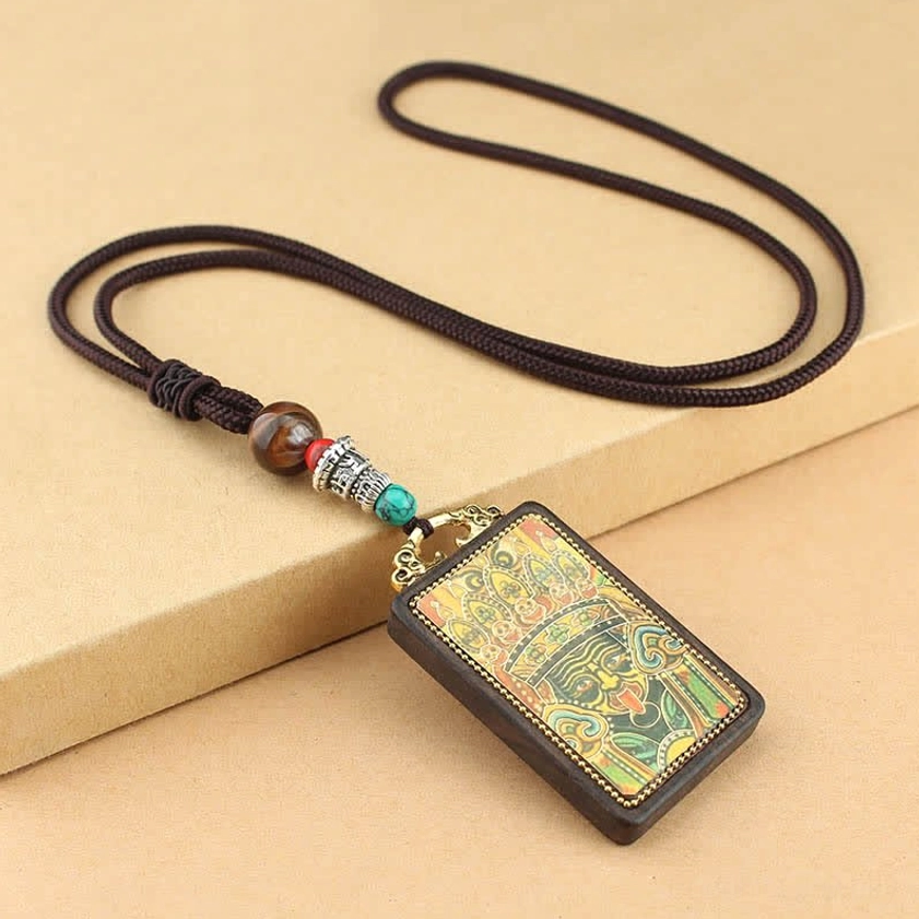 Tibetan Buddhist Thangka ebony wood pendant necklace side oblique angle, showing colorful religious mural carving with woven rope