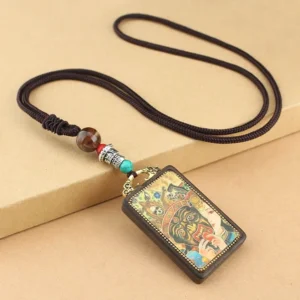 Five Gods of Wealth Thangka ebony wood pendant necklace with braided cord, top-down view on neutral desktop showing intricate carved deity artwork and decorative beads