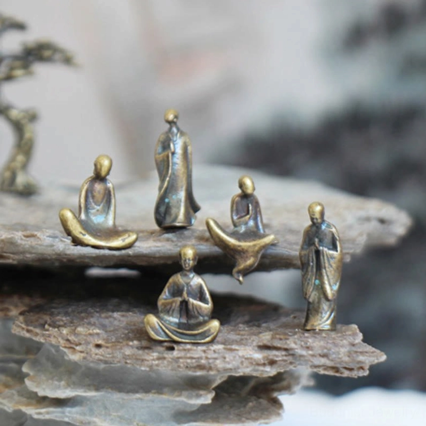 Group of five mini bronze Buddha figurines in various sitting and standing meditation postures on layered rock display stand, overhead angle