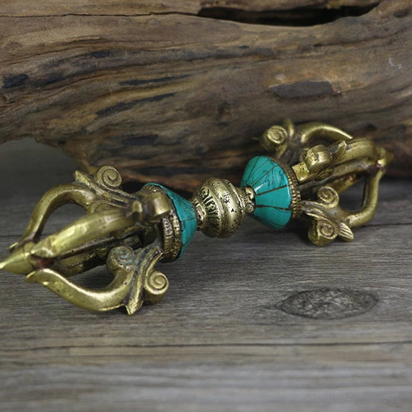 Vajra dorje flatlay showing symmetric turquoise accents and forged brass construction on wooden surface