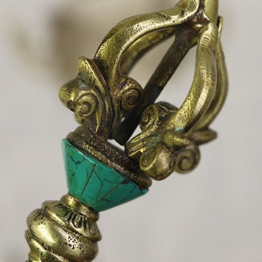 Detailed close-up of vajra dorje head section featuring conical turquoise inlay and carved scroll decorations