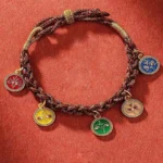 Five wealth deities braided string bracelet with multicolor enamel pendants on red fabric background - Buddhist prosperity charm