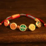 Five wealth deities braided Buddhist luck bracelet with multicolor woven rope and gold enamel charms showing traditional Buddhist iconography