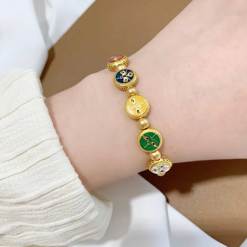 Side close-up of five wealth gods bracelet on wrist showing gold beads and colorful Buddhist deity charm details