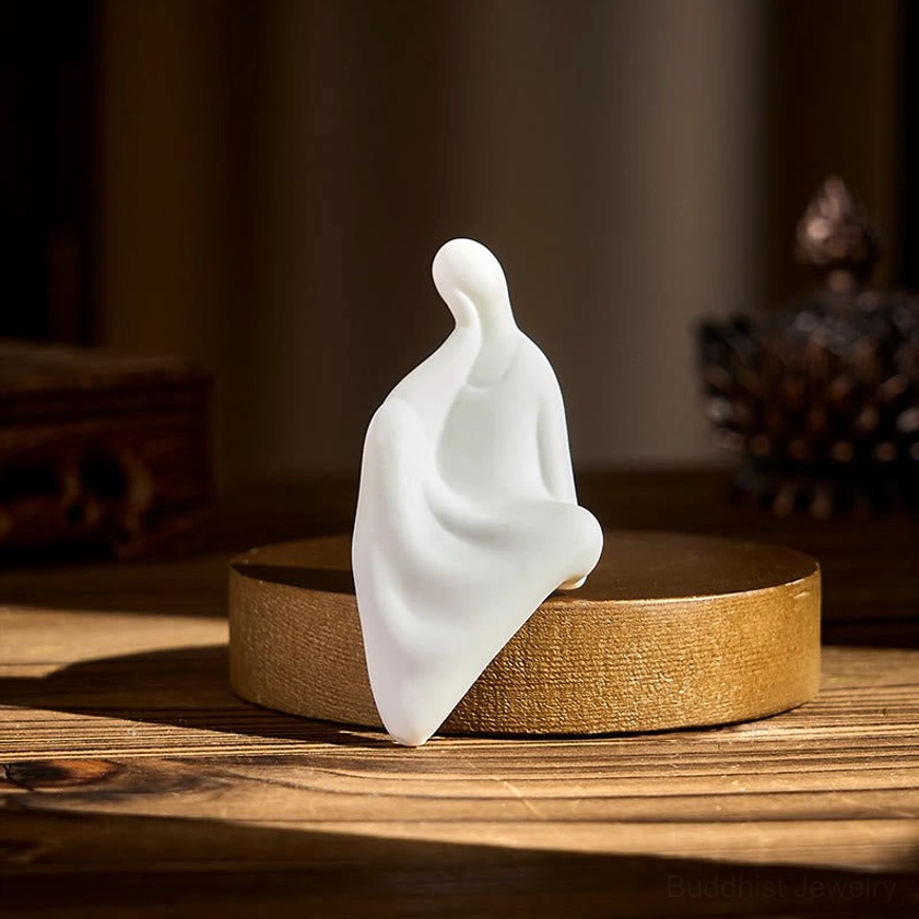 Handcrafted Buddha ceramic sculpture on round wenge wood display base, side profile view on warm wooden surface