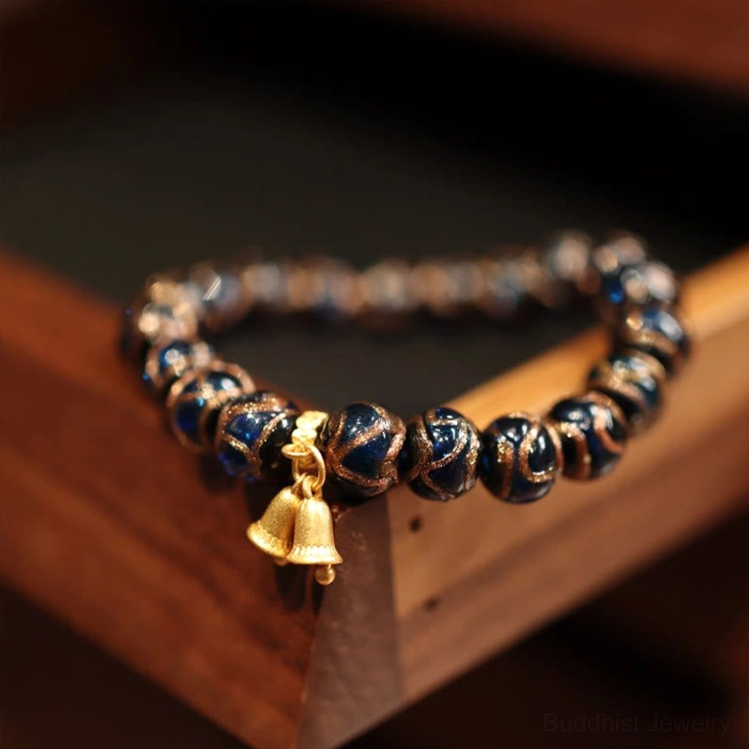 Fortune bead bracelet with double bell charm pendant, dark glossy beads and blue enamel accents close-up