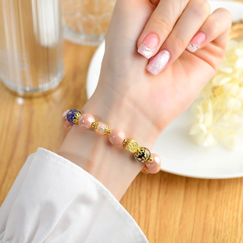 Woman wearing incense ash liuli glass nine-tailed fox bracelet on her wrist during mealtime, showing pink nail art and comfortable fit, close-up side angle