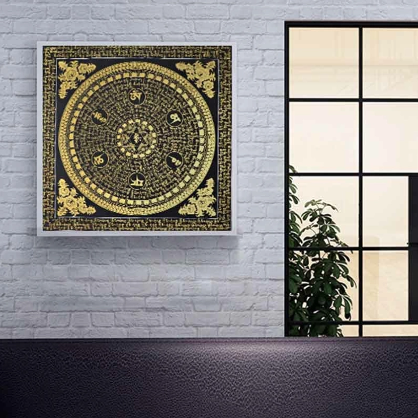 Framed black-gold Om Mani Padme Hum mandala thangka hanging on white brick wall with window - minimalist Buddhist spiritual artwork